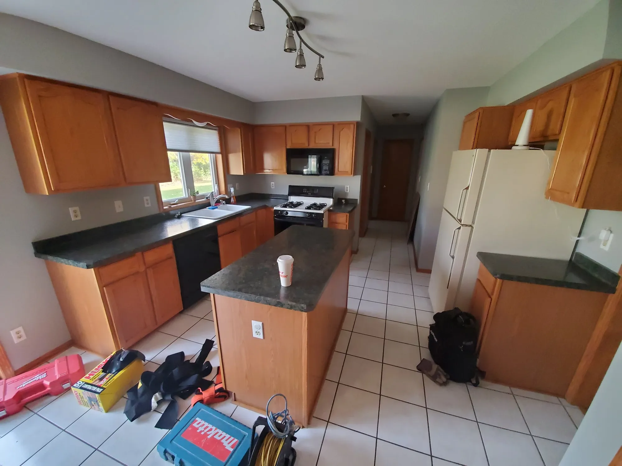 Kitchen before remodeling, with oak cabinets and dark laminate counters
