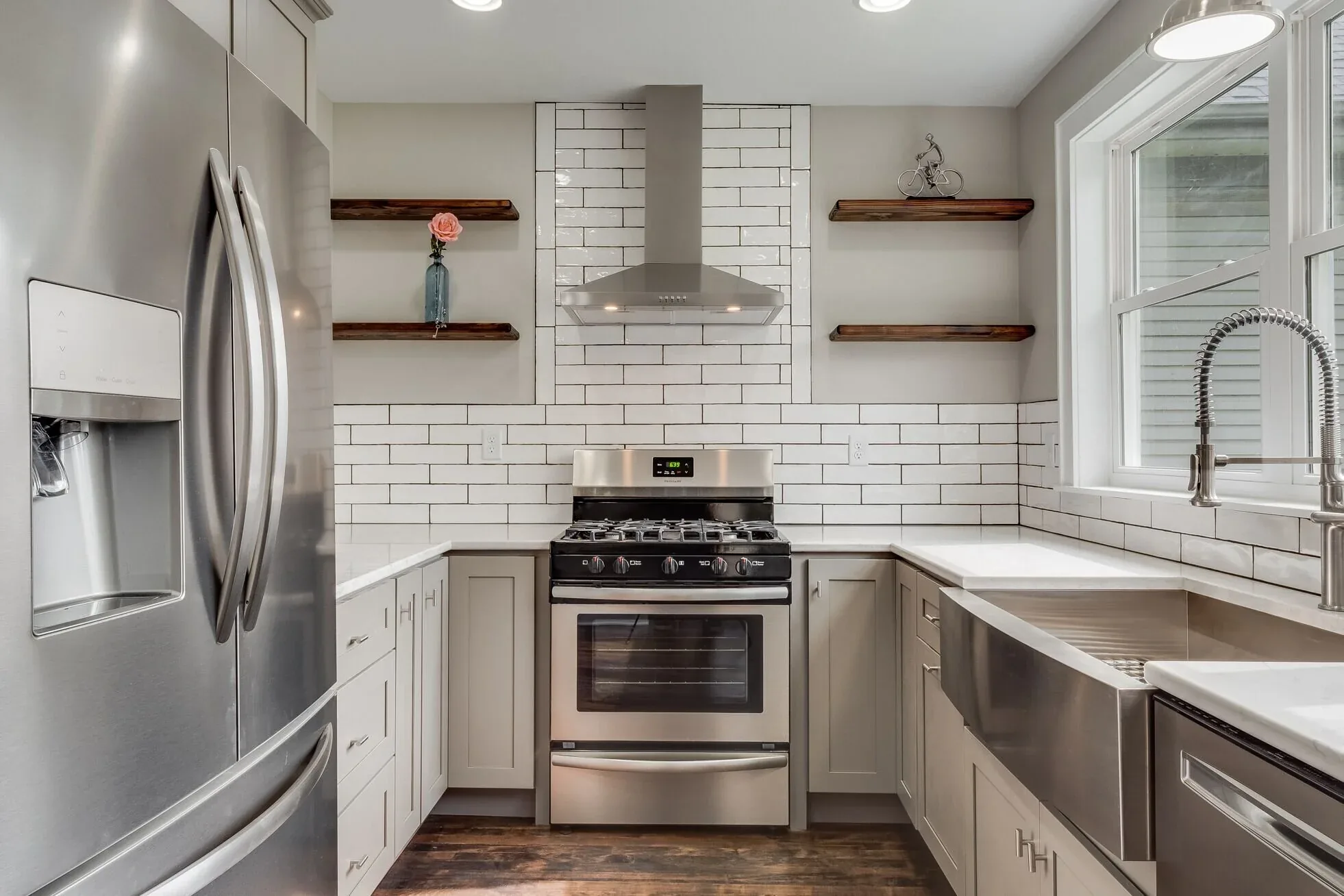 Remodeled kitchen with grey cabinets, subway tile backsplash and open wood shelving
