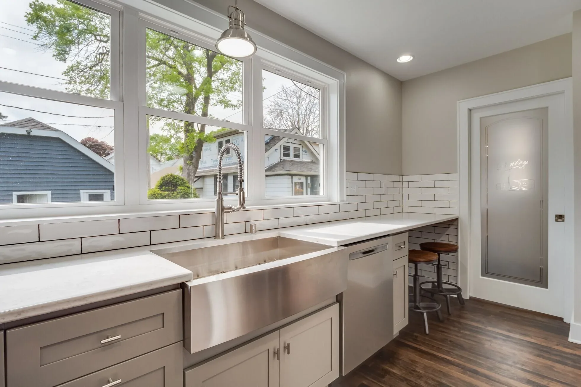 Wide kitchen remodel with a stainless farmhouse sink, quartz counters and a run of windows